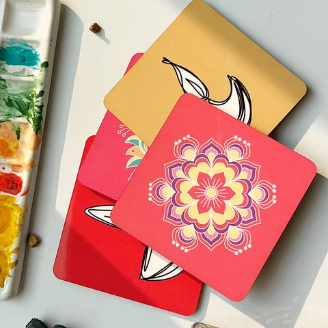Stack of colorful, eco-friendly coasters with floral and leaf designs on a white table beside a paint palette