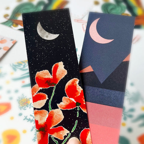 Two artistic bookmarks with crescent moon designs and night themes, featuring red flowers and abstract mountains