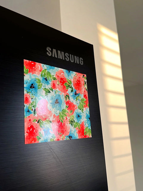 Watercolor-style floral painting magnet attached to black Samsung fridge.
