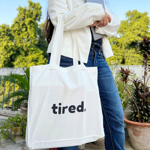 Minimalist tired quote tote bag placed on a desk with notebooks and a drink