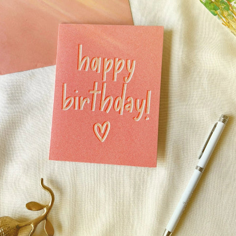 Handmade pink birthday card with “happy birthday!” and heart illustration.