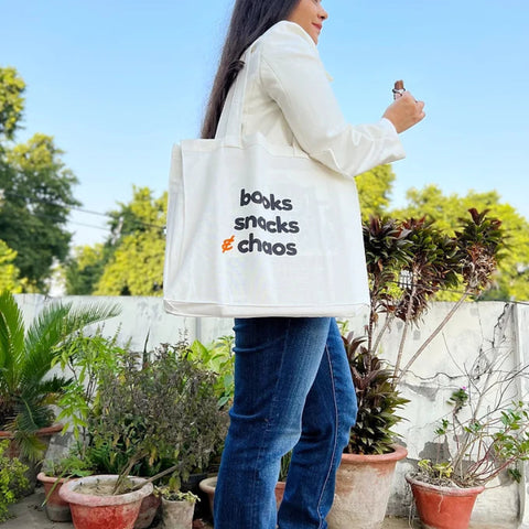 White cotton tote bag with reader humor design held by woman in white