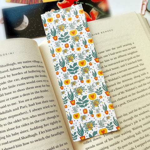 "Botanical pattern bookmark with potted plants held between book pages"