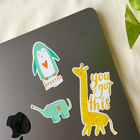 "Colorful vinyl stickers of cartoon animals with positive affirmations on a MacBook"
