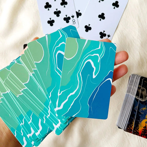 Hand-painted deck of cards with forest silhouette and cosmic sky artwork.